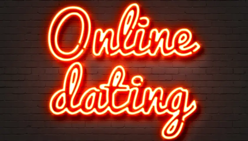 Neonowy napis "Online dating" na ceglanej ścianie. Szukasz odpowiedzi, gdzie poznać dziewczynę w sieci?