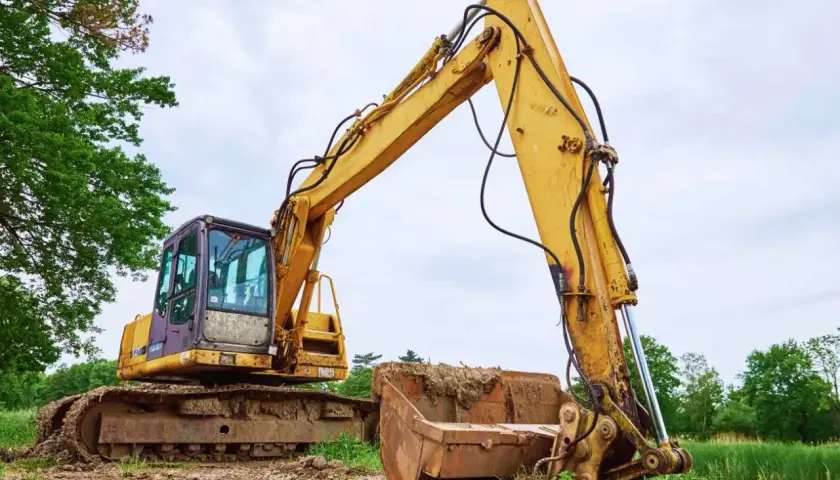 Żółta koparka gąsienicowa na placu budowy. Zastanawiasz się, jaki olej hydrauliczny do koparki będzie najlepszy?