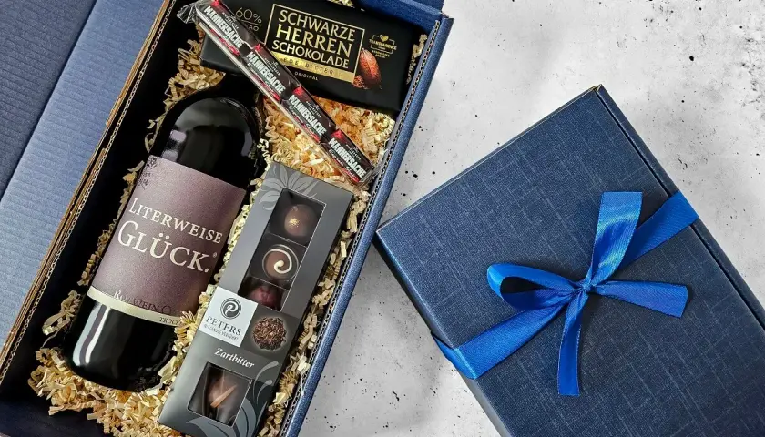 Ein edler Geschenkkorb zum 50. Geburtstag für einen Mann: Rotwein, dunkle Schokolade und Pralinen.