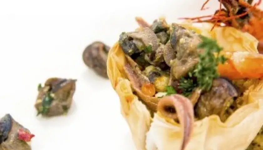 Wykwintne danie ze ślimaków w cieście filo, idealne na ślimak catering Kraków. Krewetka i zioła dopełniają kompozycję.