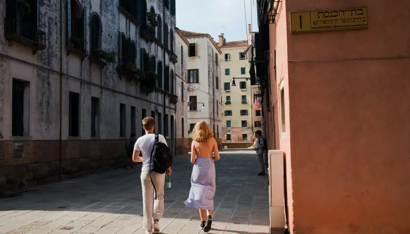 Coppia passeggia in una stretta via di Venezia, una delle più belle città da visitare nel nord Italia.