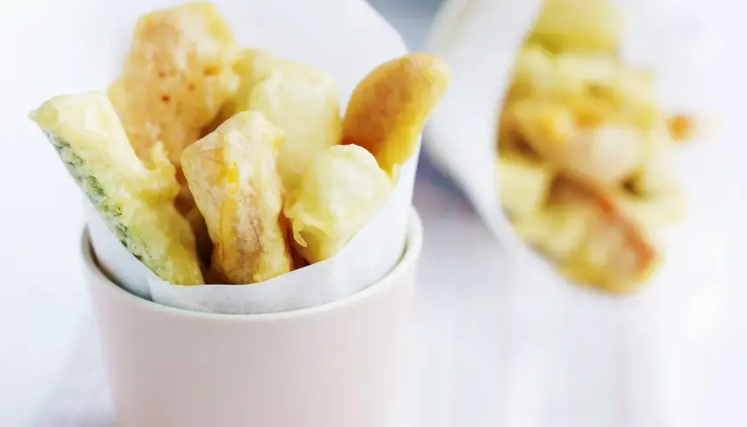 Verdure croccanti immerse in una leggera pastella per verdure fritte, servite in un contenitore rosa.