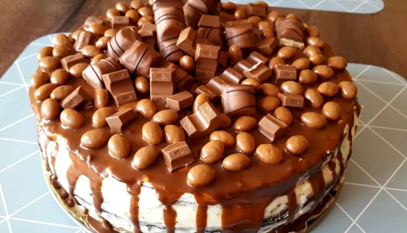 Pyszny tort kinder obficie udekorowany batonikami i czekoladowymi kuleczkami.