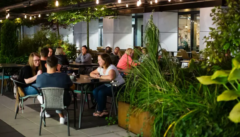 Wieczorny relaks w jednej z nowych restauracji w Łodzi. Ludzie siedzą przy stolikach, delektując się posiłkami i rozmowami.