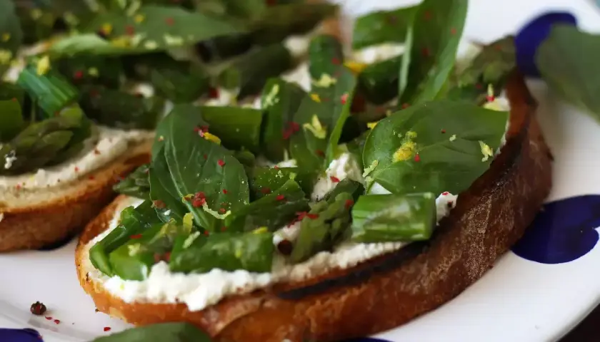 Krispigt rostat bröd med krämig ost, sparris och basilika. Ett perfekt bruschetta recept för en lätt lunch eller förrätt.
