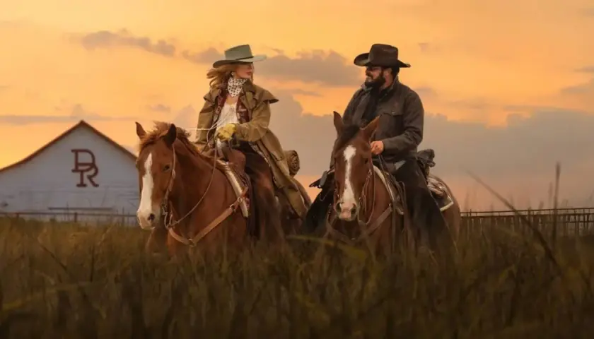 Deux cavaliers, Beth et Rip, sur leurs montures, devant une grange au coucher du soleil. Un aperçu du yellowstone saison 5 résumé.