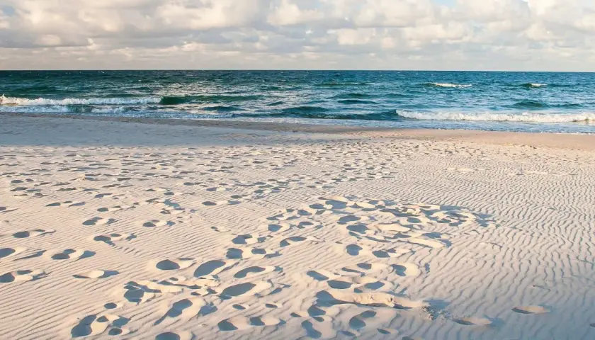 Piasek na plaży, ślady stóp i fale Bałtyku. Idealne miejsce, by pomyśleć, gdzie nad morze.