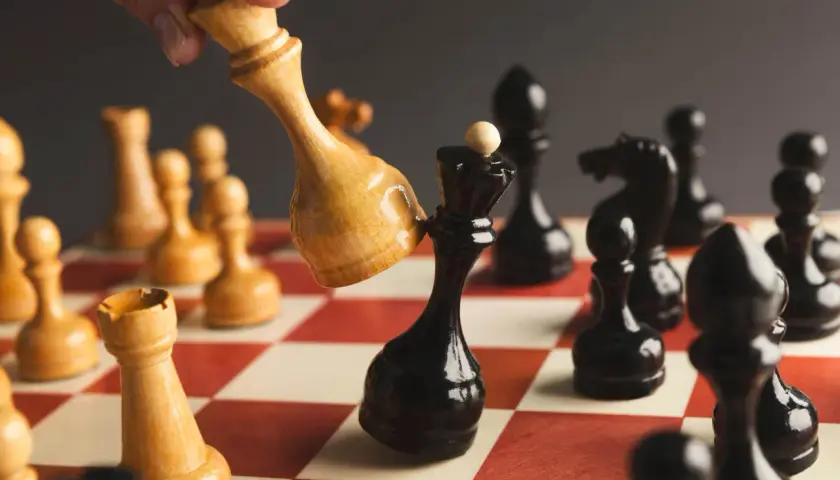 Ręka przesuwa jasnego króla, by zbić czarnego króla. Strategia jak sprzedać akcje.