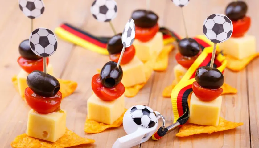 Ambiance parfaite pour une soiree foot : petits fours avec des ballons, des olives, des tomates et des drapeaux allemands.