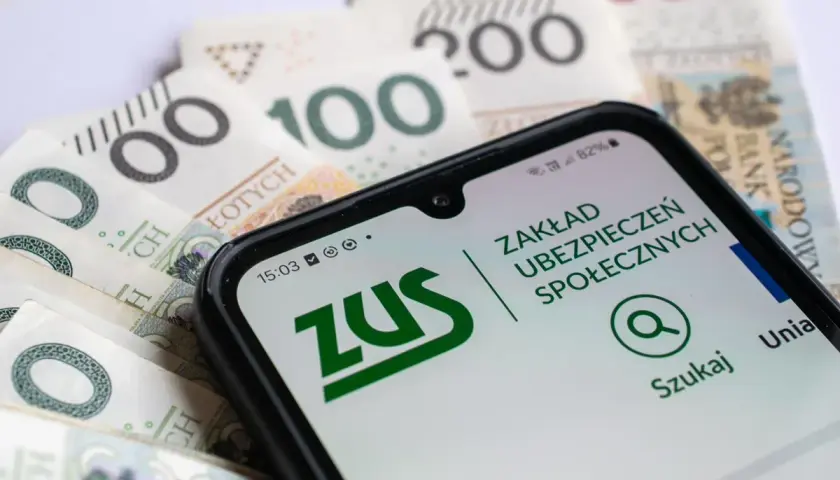 Smartfon z aplikacją ZUS na tle polskich banknotów. Ułatwia przeliczenie emerytury i sprawdzenie świadczeń.