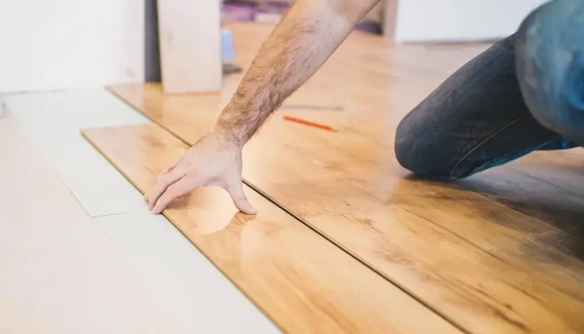 Installazione di parquet laminato: un uomo posa le tavole, mostrando come tagliare spc.