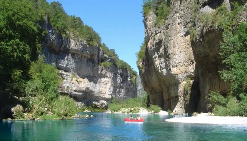 Spływ kajakiem po turkusowej rzece w wąwozie Gorges du Tarn. Majestatyczne, skalne ściany porośnięte zielenią.