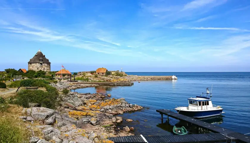 Kamienna wieża i domki na skalistej wysepce nad spokojnym Bałtykiem. Ile wysp jest na Bałtyku? Tyle, ile potrzeba, by poczuć spokój.