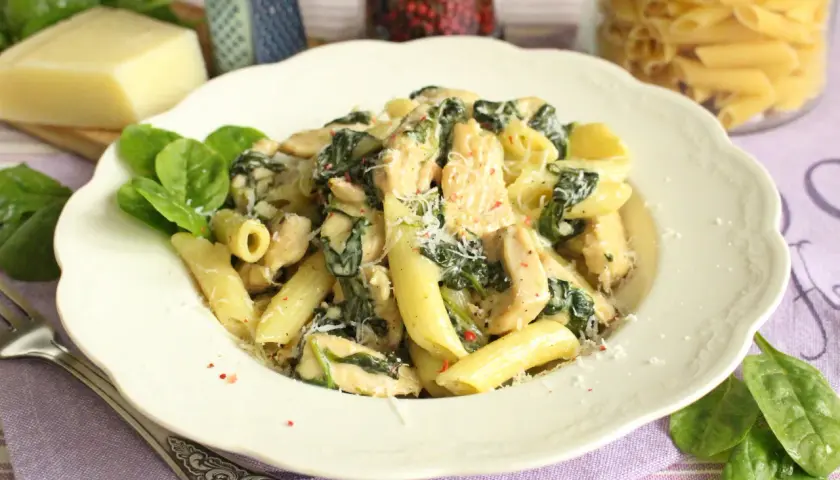 Penne z kurczakiem i szpinakiem w kremowym sosie, posypane parmezanem. Pyszne danie, które zachwyci każdego.