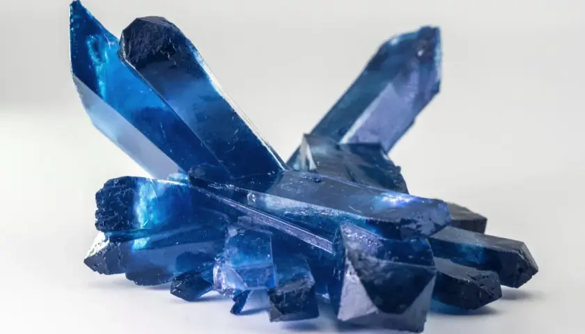 Ein Cluster tiefblauer Kristalle, die an gefrorene Eisspitzen erinnern. Die Bedeutung eines blauen Steins wird oft mit Ruhe und Klarheit assoziiert.