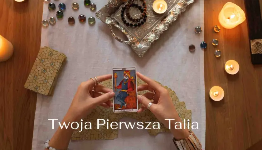 Ręce trzymają kartę Tarota "Cesarz". Wokół świece, kamienie i talia kart. Idealne na początek przygody z wróżeniem, jakie karty tarota dla początkujących.