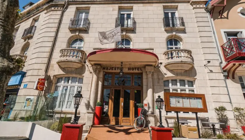 Façade de l'hôtel Majestic à Châtelaillon-Plage avec son entrée principale en bois et un drapeau blanc.