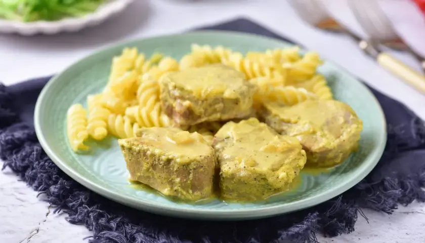 Soczyste polędwiczki w sosie musztardowym podane z makaronem fusilli na zielonym talerzu.