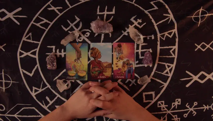 Horoskop miesięczny Lew Tarot: karty i kryształy na tle runicznym.