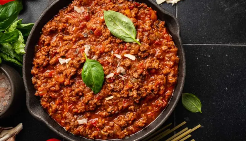 Un delicioso plato de spaghetti bolognese original, con carne picada, tomate y albahaca fresca.