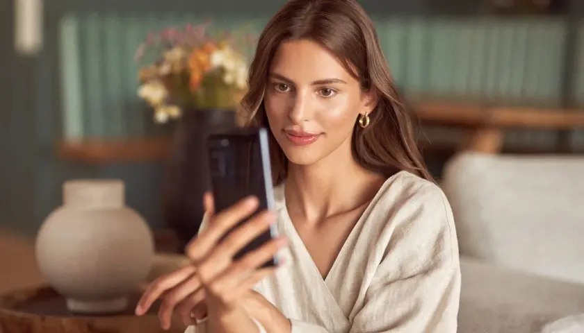 Kobieta robi sobie selfie telefonem, patrząc na ekran.