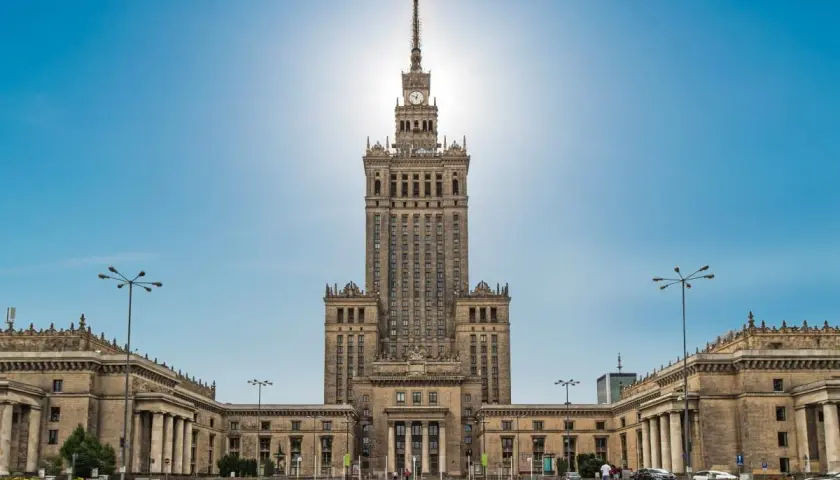 Imponujący Pałac Kultury i Nauki w Warszawie, jego monumentalna wysokość dominuje nad placem.