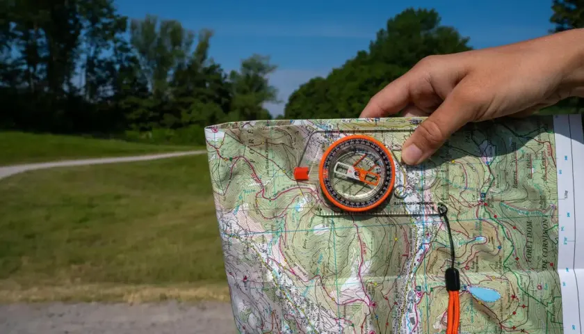 Biegi na orientację jak czytać mapę: kompas i mapa topograficzna w dłoni, gotowe do nawigacji w terenie.