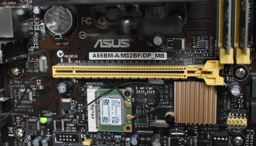 Carte mère ASUS A55BM-A/M32BF/DP_MB avec branchement carte mère visible, incluant une carte Wi-Fi et des connecteurs.