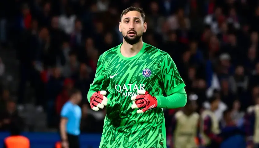 Gianluigi Donnarumma, bramkarz PSG, w zielonej koszulce i czerwonych rękawicach, gotowy do obrony.