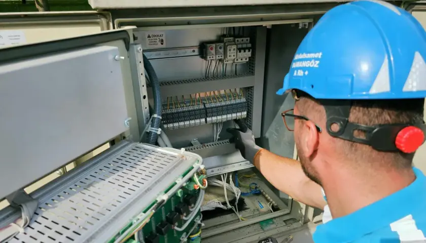 Elektryk pracuje przy panelu sterowania, przygotowując oświadczenie o gotowości instalacji przyłączanej.