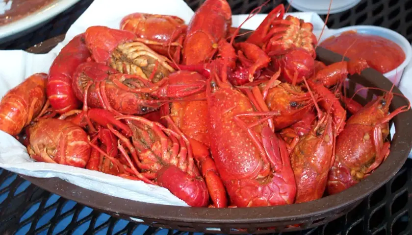 En korg full med saftiga kräftor, redo för en härlig seafood boil. En liten skål med röd sås står bredvid.