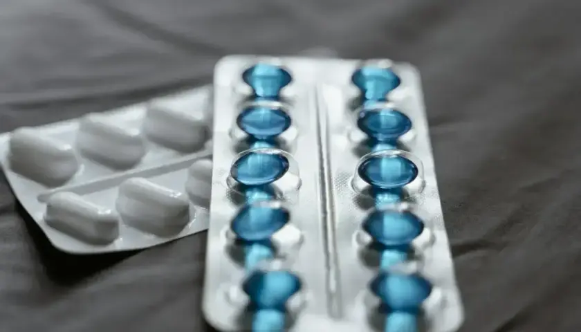 Dwa opakowania leków: jedno z białymi tabletkami, drugie z niebieskimi kapsułkami. Na co **egzysta na co**?