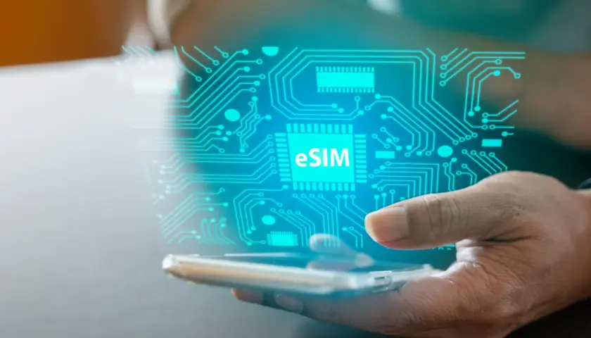 Dłoń trzyma smartfon, nad którym unosi się cyfrowy obwód z napisem eSIM. To przyszłość łączności, esim bez abonamentu.