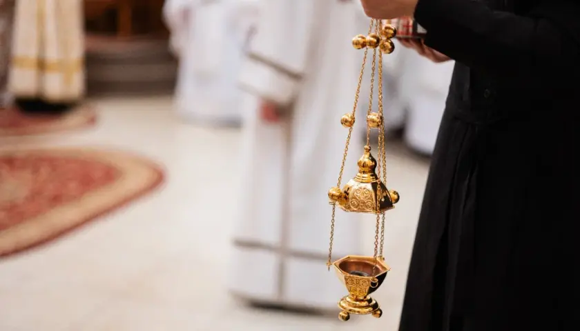 Złota kadzielnica w ręku osoby w czarnej szacie. Czy msza w środę popielcową jest obowiązkowa?