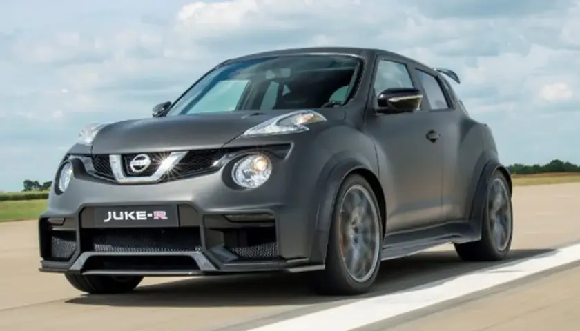 Nissan Juke-R gris oscuro, con alerón trasero y llantas deportivas, circulando por una pista.