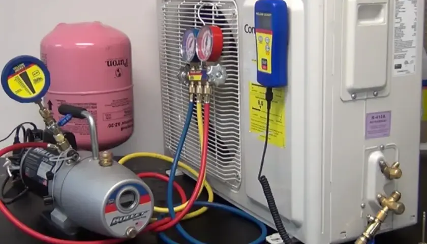 Equipo para hacer vacío a un aire acondicionado: bomba, manómetros, tanque de refrigerante y mangueras.