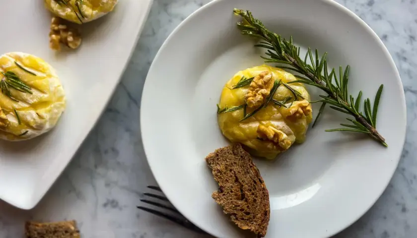 Deliziosi tomini in friggitrice ad aria, guarniti con noci e rosmarino, serviti con pane integrale.