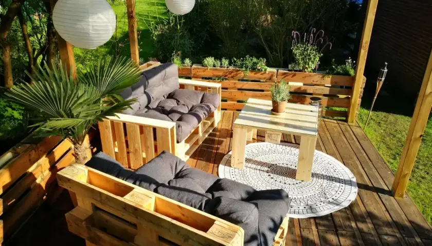 Gemütliche Lounge-Ecke mit Palettenmöbeln. Tolle Paletten Ideen für den Garten, mit Sitzbank, Tisch und Pflanzen.