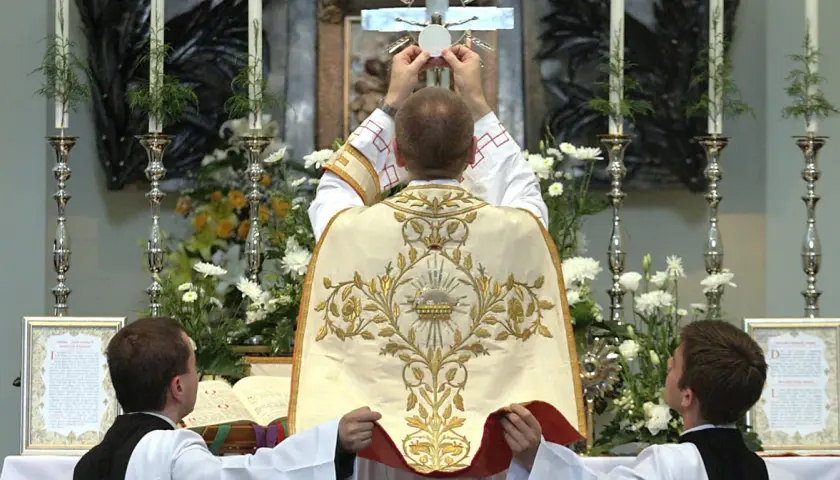 Kapłan podnosi hostię do krzyża. To nie jest czarna msza, lecz uroczysta msza święta.