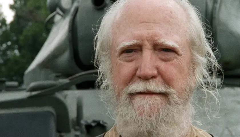 Hershel Greene, członek obsady "Żywych trupów", z siwą brodą i włosami, na tle pojazdu.