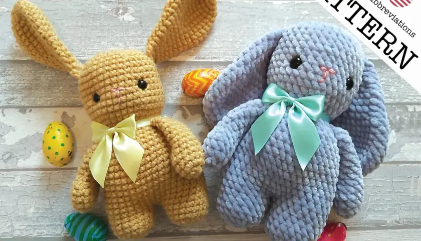 Due coniglietti amigurumi, uno color miele e uno azzurro, con fiocchi e uova di Pasqua.