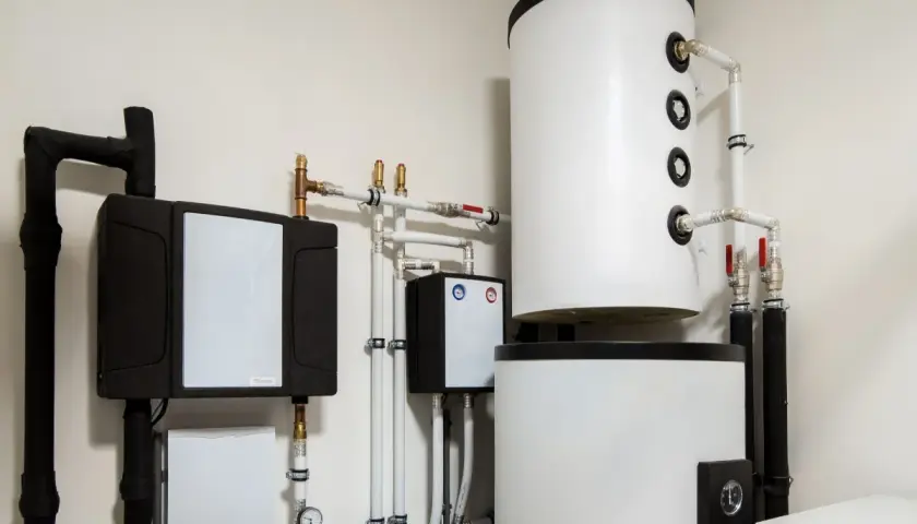 Instalacja pompy ciepła z zasobnikami i rurami. Widoczny panel sterowania, który może wpływać na histerezę pompy ciepła, zapewniając optymalną pracę systemu.
