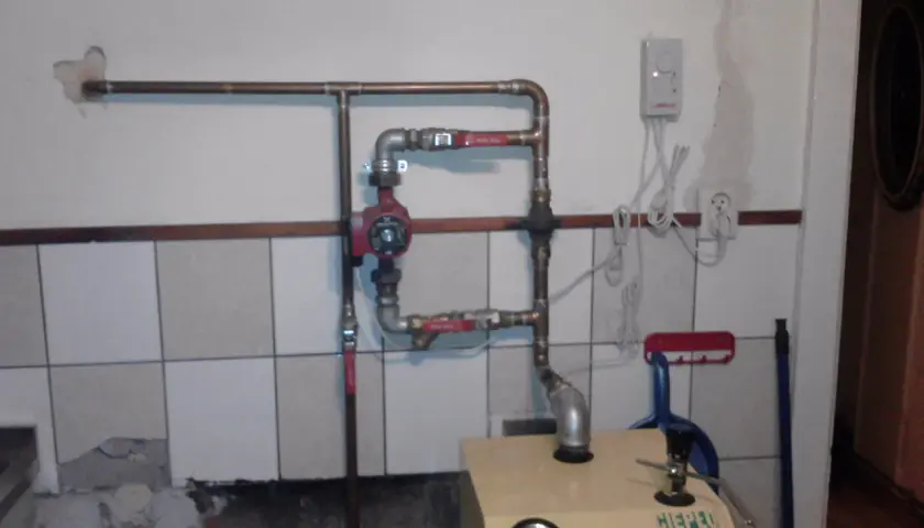 Montaż pompy CO w układzie otwartym. Widoczna instalacja hydrauliczna, czerwona pompa, zawory i fragment kotła.