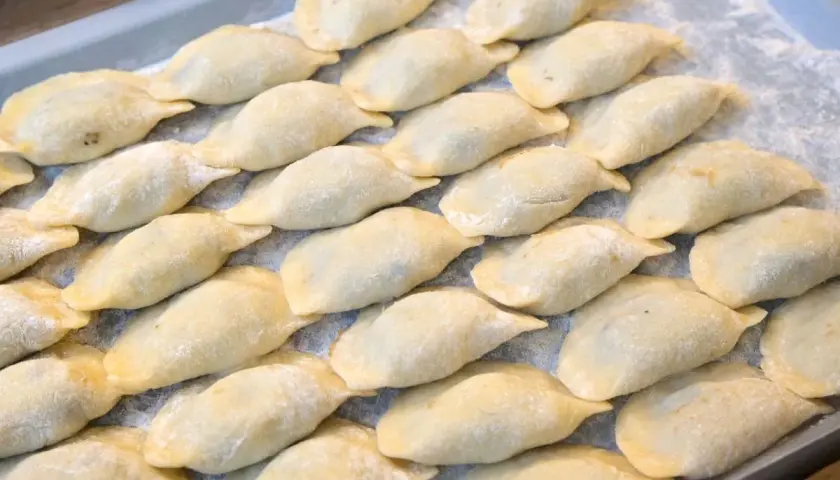 Ułóż surowe pierogi na tacy, posypane mąką, aby wiedzieć, jak przechowywać pierogi.