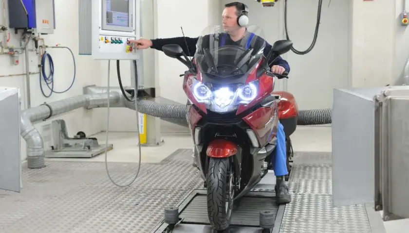 Mechanik sprawdza motocykl na hamowni. Regularny przegląd motocykla 125 zapewni jego sprawność.