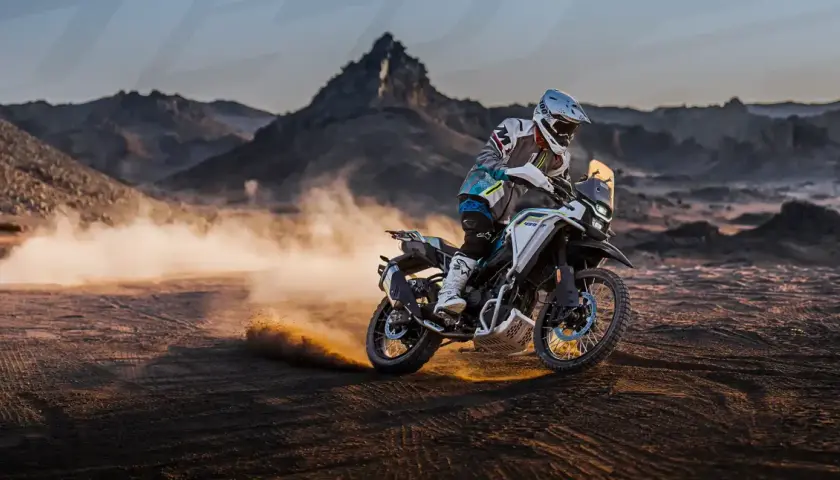 Motociclista en una CF Moto 450 MT, levantando polvo en un paisaje desértico. Conoce la cf moto 450 mt ficha técnica.