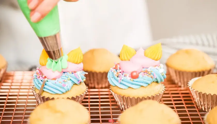 Decorazione di cupcake con crema al burro colorata, zuccherini e perline.