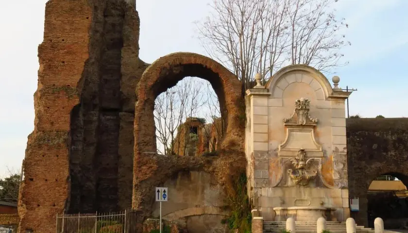 Antica porta furba metro, con fontana e rovine romane.
