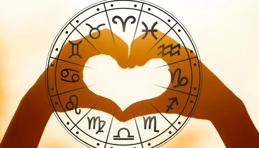 Dłonie tworzą serce na tle koła zodiaku, gdzie uran w koziorożcu symbolizuje przełom w dążeniu do celu.
