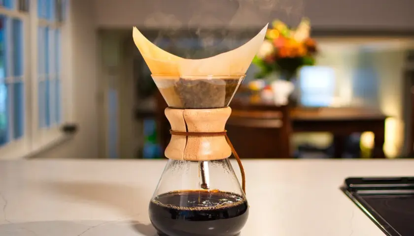 Dampf steigt auf bei der Chemex Zubereitung. Frisch gebrühter Kaffee tropft in die Glaskaraffe.